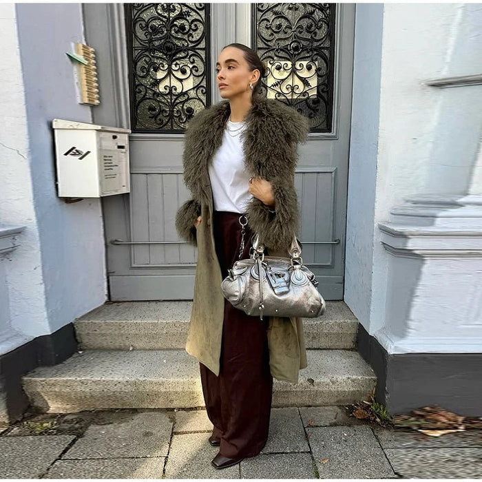 Woman in a khaki coat with a shaggy faux fur collar over a white tee and wide-leg pants